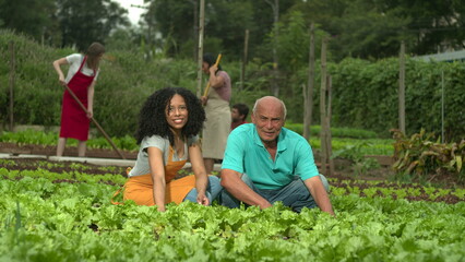 Small farmers smiling at camera working on a community farm cultivating sustainable organic food