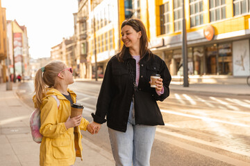 Fototapeta premium Close up view of mother and daughter walk with drinks and luffing 