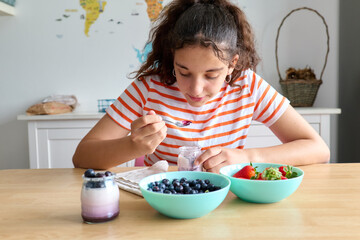 Teenage girl having a healthy breakfast with yogurt and fresh berries, healthy eating concept