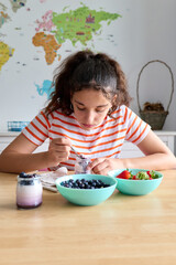 Teenage girl having a healthy breakfast with yogurt and fresh berries, healthy eating concept