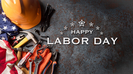 Happy Labor day concept. American flag with different construction tools and the text on dark stone...