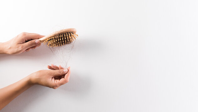 Healthcare problem concept. Woman hand holding hair loss or hair fall in comb on white background.