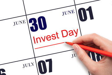 Hand drawing red line and writing the text Invest Day on calendar date June 30.  Business and financial concept.