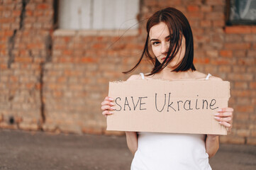 Women with Poster Save Ukraine. A woman with a belligerent look looks into the Camera.