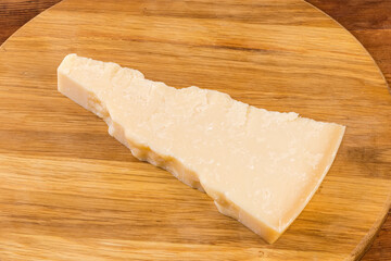 Piece of the hard cheese on a round cutting board