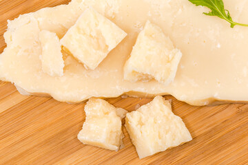 Hard cheese pieces on wooden surface, top view close-up