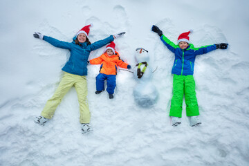 Family in snow together with snowman wear Santa hats top view