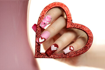 Pink multicolored manicure on long nails with hearts.