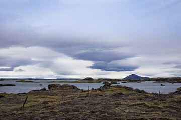 Volcanic rocks in and around a lake in northern Iceland. Volcano crater on the horizon.