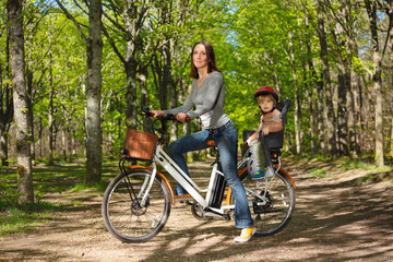 Naklejka premium Mother with a child on electric bike in the park