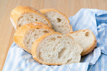 Fresh sliced baguette bread on wooden table. Healthy eating breakfast.