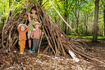 Three children boys and a girl build hut of branches