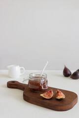 Homemade fig jam in the jar and fresh fig on the rustic wood board. Copyspace.