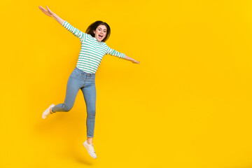 Fototapeta na wymiar Full body image of delighted cheerful screaming girl flying jumping up enjoy weekend isolated on yellow color background