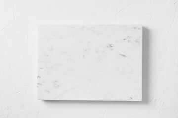 Empty white marble board on light gray stone table. Food and cooking background with free space for...