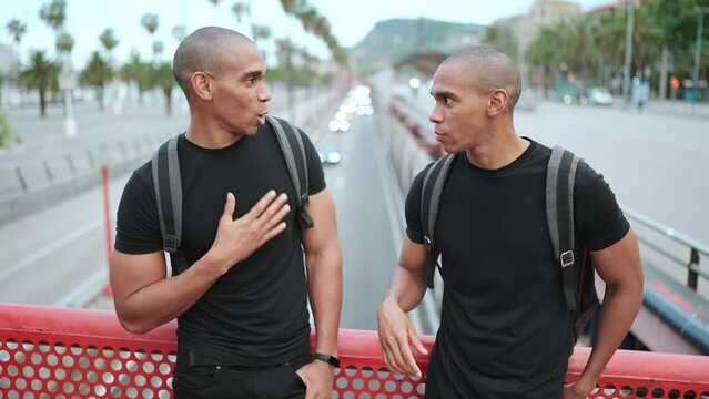 Two handsome bald African brothers talking on the bridge outdoors 