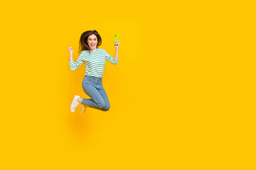 Full length photo of cute overjoyed girl celebrate victory receive many likes of her post isolated on yellow color background