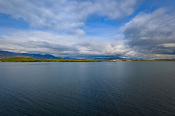 Landscape of meadows and mountain ranges seen from the shore near Reykjavik, Iceland