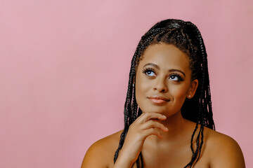 portrait of young adult thoughtful beauty black woman with hand on chin braid hair on pink background studio shot - obrazy, fototapety, plakaty
