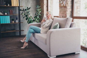 Photo of cheerful positive lady ceo dressed jacket sitting sofa communicating modern gadget indoors...