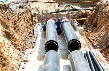Construction works on large iron pipes at a depth of excavated trench
