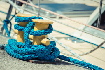 Thick blue rope and yellow bollards on wharf using for anchorage of yachts