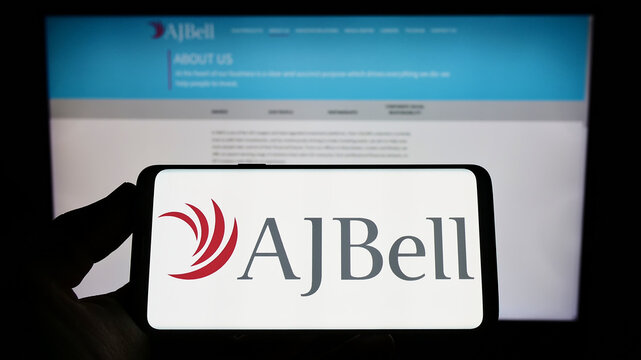 Stuttgart, Germany - 06-18-2022: Person holding mobile phone with logo of British financial company AJ Bell Plc on screen in front of business web page. Focus on phone display.