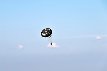 tourists hover above the water with a parachute tied to a boat