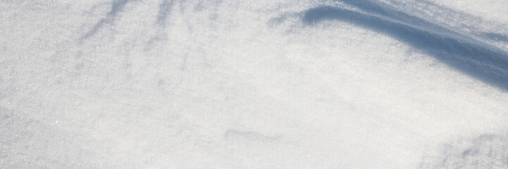 Fototapeta premium Beautiful winter background with snowy ground. Natural snow texture. Wind sculpted patterns on snow surface. Wide panoramic texture for background and design.