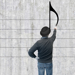 Künstler malt einen Notenschlüssel auf einer Betonwand