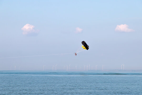 tourists hover above the water with a parachute tied to a boat