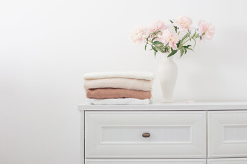 pink peonies in vase and female clothes in white room