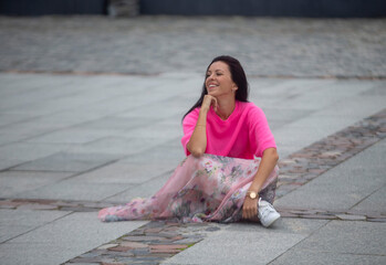 A young girl is sitting on a stone pavement