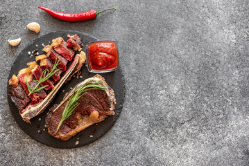 Grilled New York beef steak on the bone, herbs and spices on a stone background with copy space for...