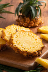 Fresh cut pineapple on a tray over dark wooden table background.