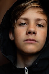 Portrait of blonde teenage boy on dark background outdoor. Low key close up shot of a young teen boy, adolescence. Selective focus. Loneliness, sadness, adolescent anxiety, emotional