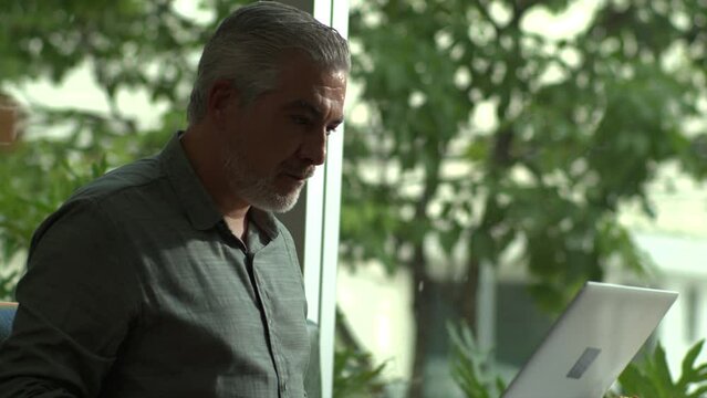 Older male entrepreneur working in front of laptop comuter sitting at coffee shop