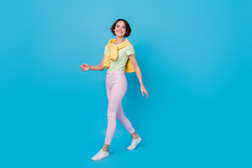 Full body photo of nice millennial brunette lady go wear t-shirt trousers footwear isolated on blue background