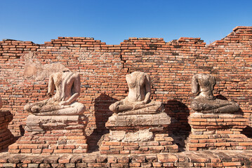 Broken ancient Buddha statue with bricks background.