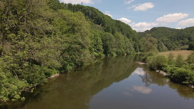 The calm brown waters of the Sieg river under a blue sky with few soft clouds. Aerial wide angle tracking shot