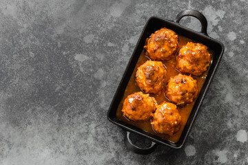 Oven baked meatballs in cast iron skillet on dark background. Top view, copy space, flat lay.