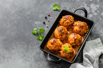 Baked spicy chicken meatballs in cast iron skillet on dark background. Top view, copy space, flat...