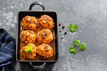 Baked spicy chicken meatballs in cast iron skillet on dark background. Top view, copy space, flat...