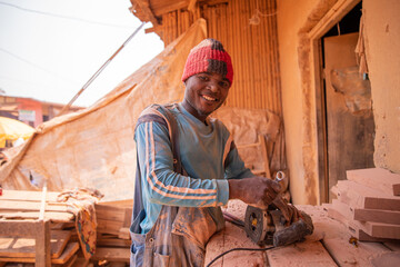 An african carpenter uses a chainsaw shaper in his workshop while working.