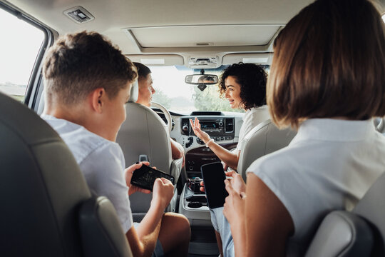 Happy Four Members Family Traveling By Minivan Car, Mother And Father With Two Teenage Children On A Weekend Road Trip