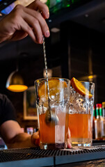 bartender hand mixing cocktail Lemonade with ice cubes in glass to customers at bar