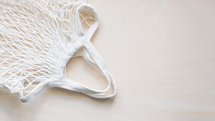 Eco friendly mesh bag on a light wooden background. Zero waste grocery shopping concept. Zero waste lifestyle. Top view, flat lay, space for text.