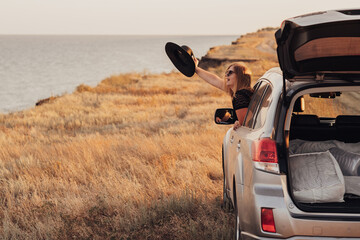 Young Woman Looks Out of the Car Window on the Sea Background, Girl Enjoying Road Trip
