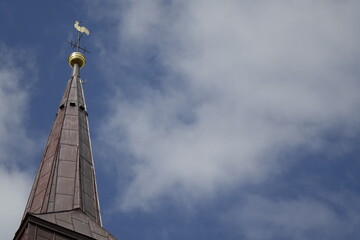 Rooftop and golden weather cock of Protestant St. Nicolai church under a cloudy spring sky...