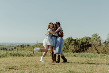 THREE HAPPY GIRLS EMBRACED IN THE COUNTRYSIDE. 